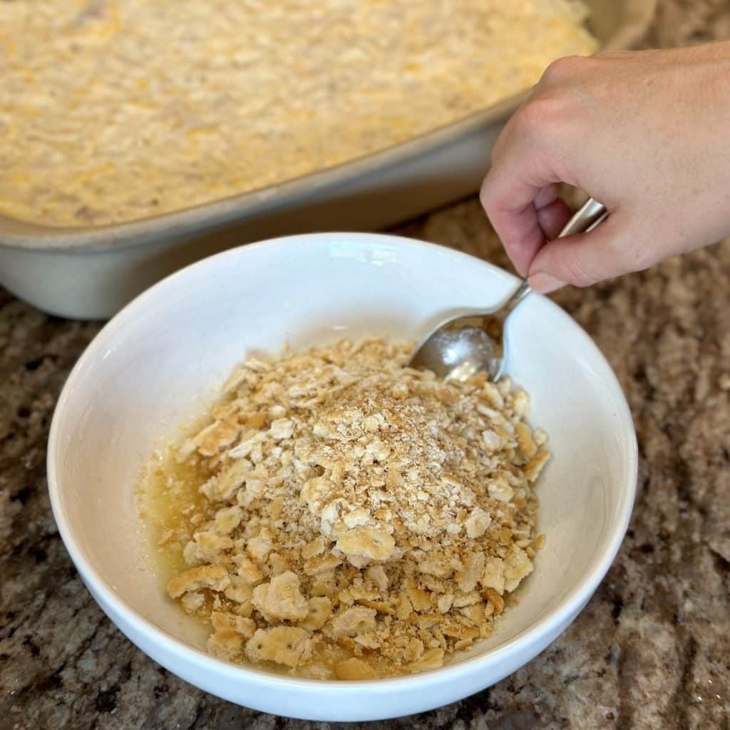 Mixing together butter and ritz crackers in a bowl.