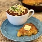 A slice of cornbread next to a bowl of chili.