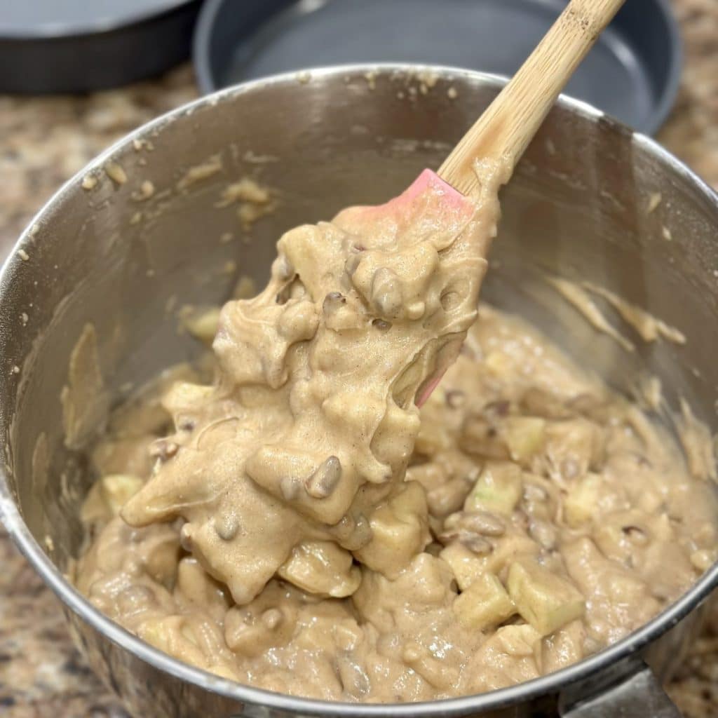 Folding apples into a cake batter.