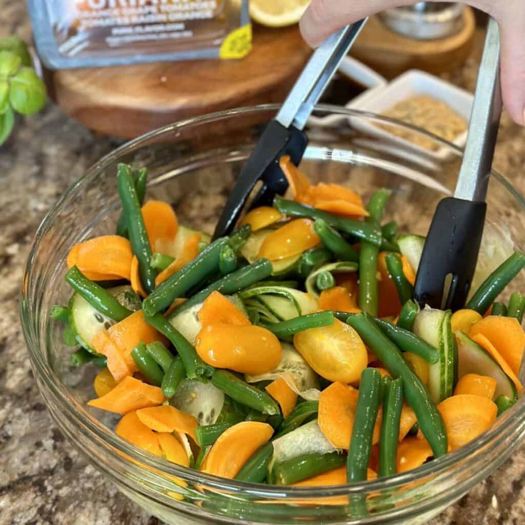 Mixing together a green bean tomato salad,