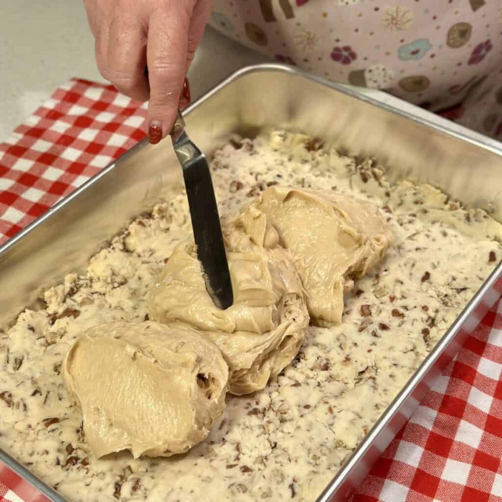 Spreading a peanut butter mixture on a shortbread crust.