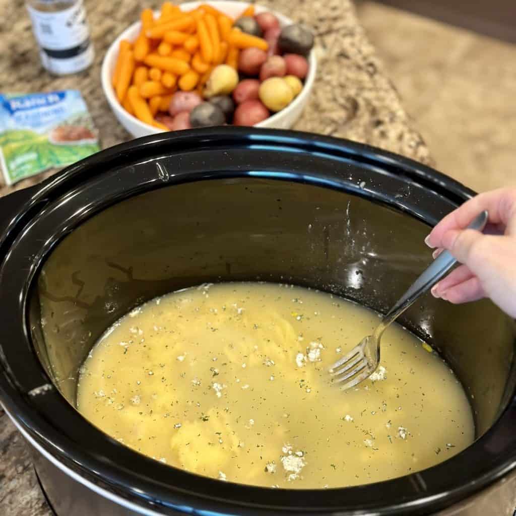 Whisking together broth and soup in a Crockpot.