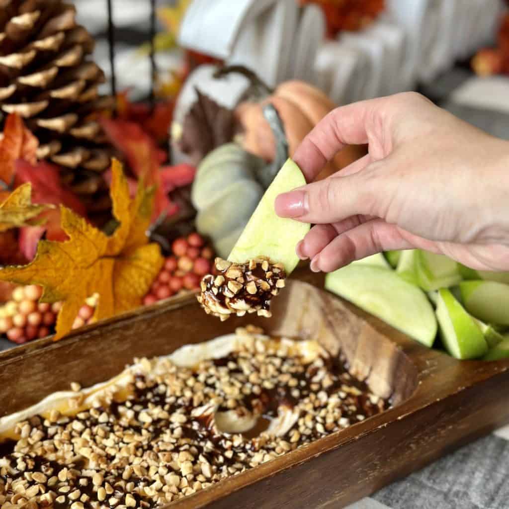 An apple slice with caramel chocolate cream cheese dip.