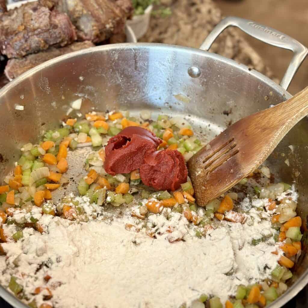 Cooking vegetables flour and tomato paste in a pan.