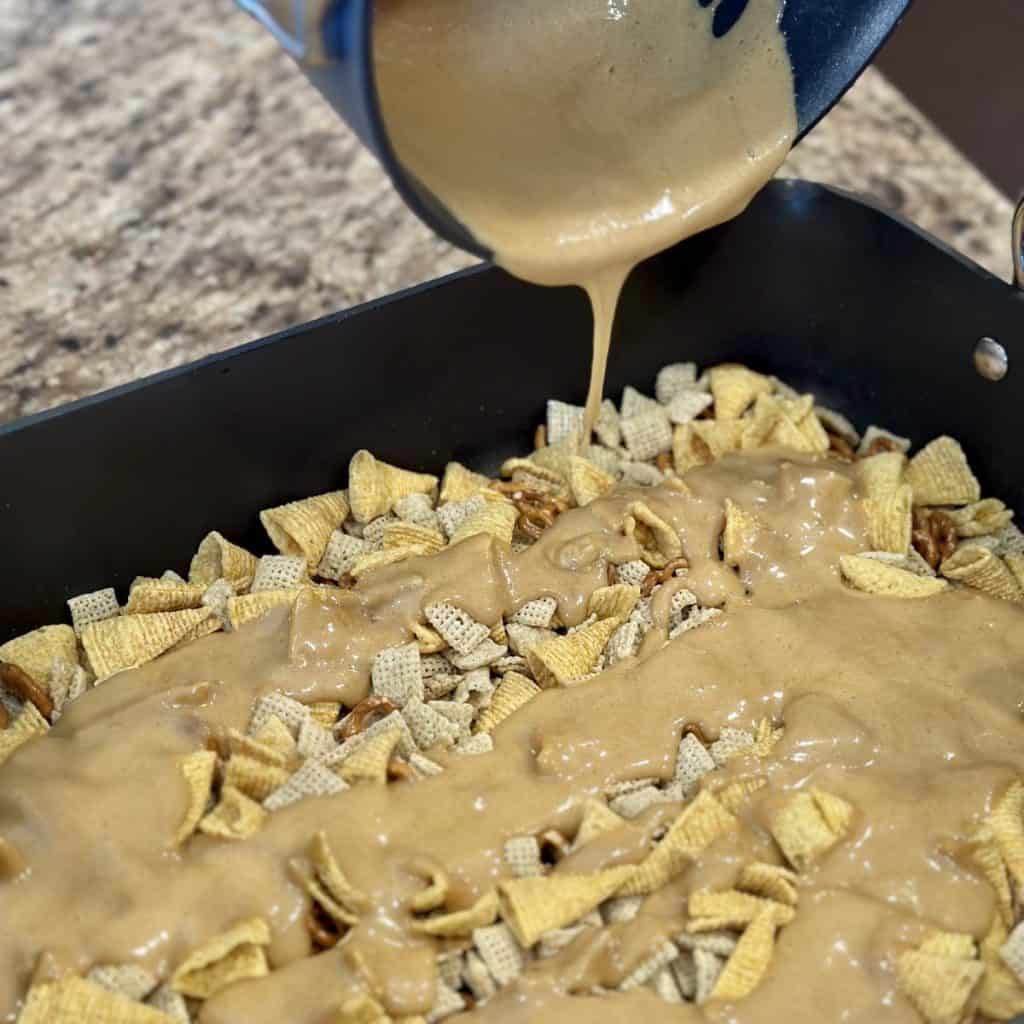 Pouring caramel sauce on top of caramel Chex mix.