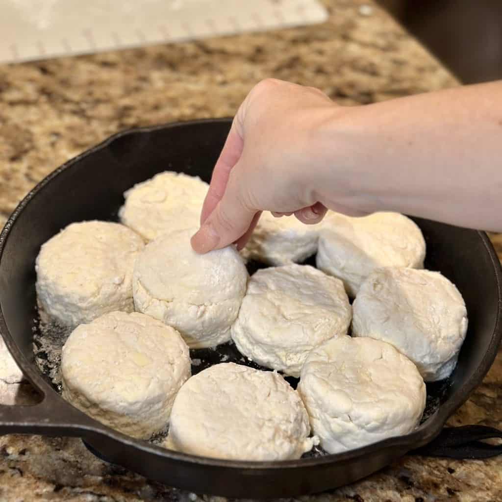 Adding biscuit dough to a cast iron skillet.