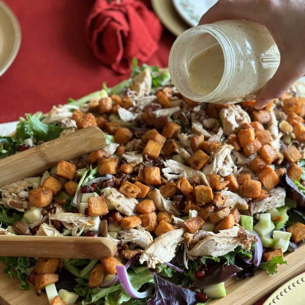 Pouring salad dressing on top of a salad.