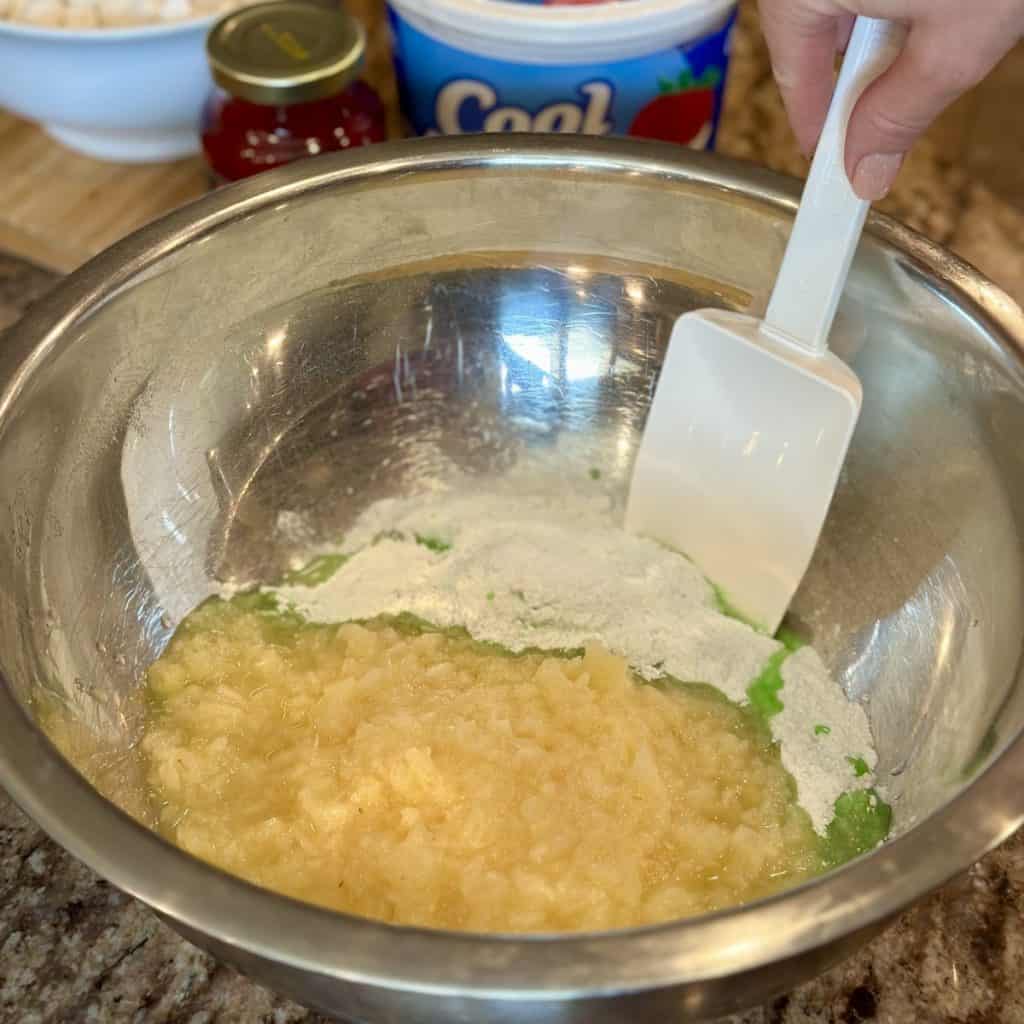 Mixing together pineapple and pistachio pudding in a bowl.