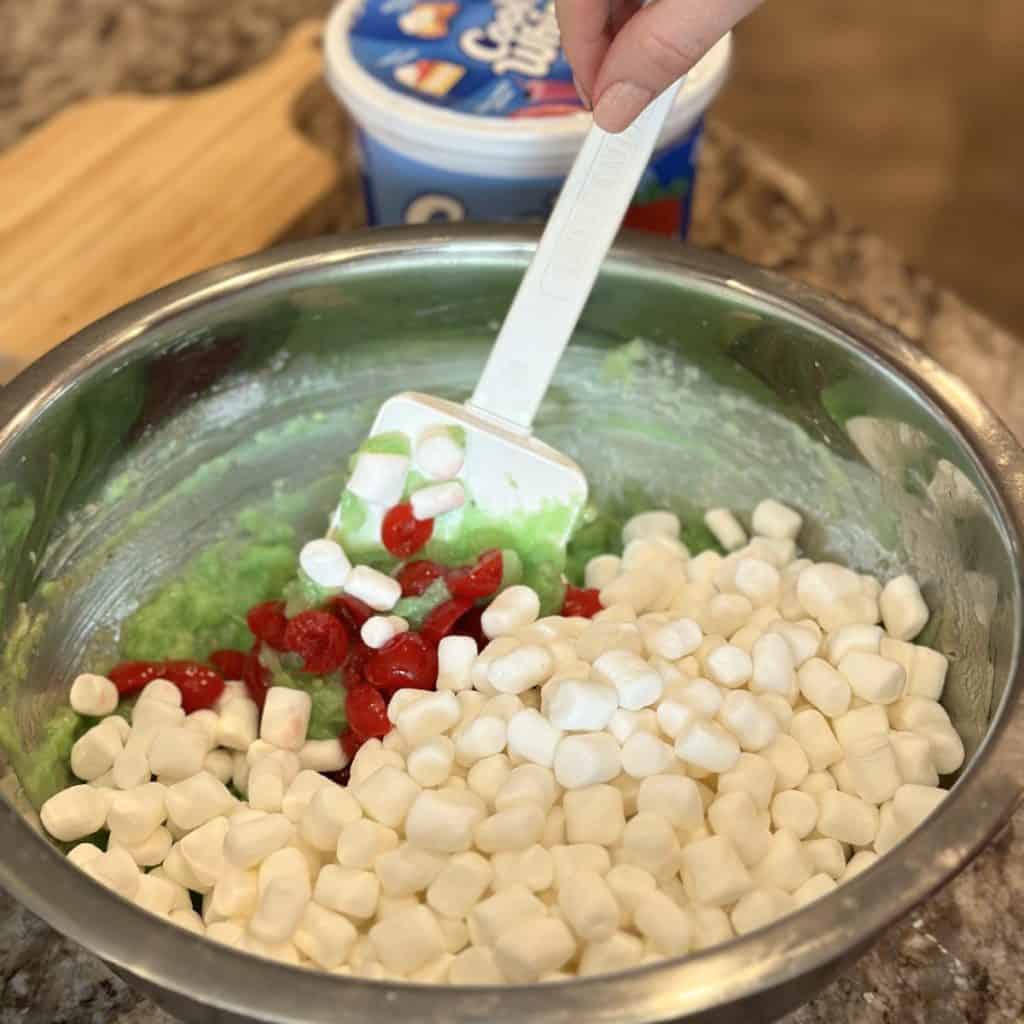 Folding marshmallows in a pistachio delight salad.