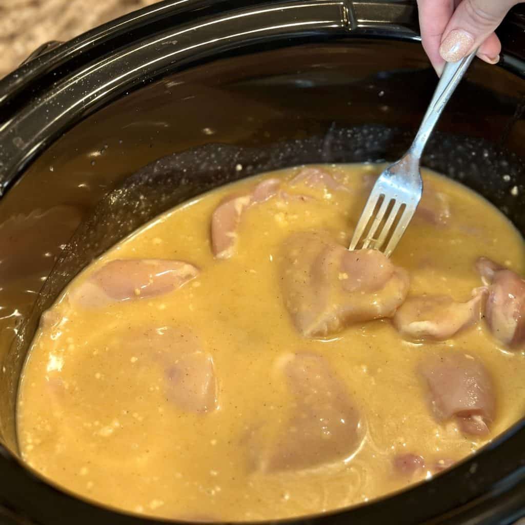 Adding raw chicken to a crockpot.