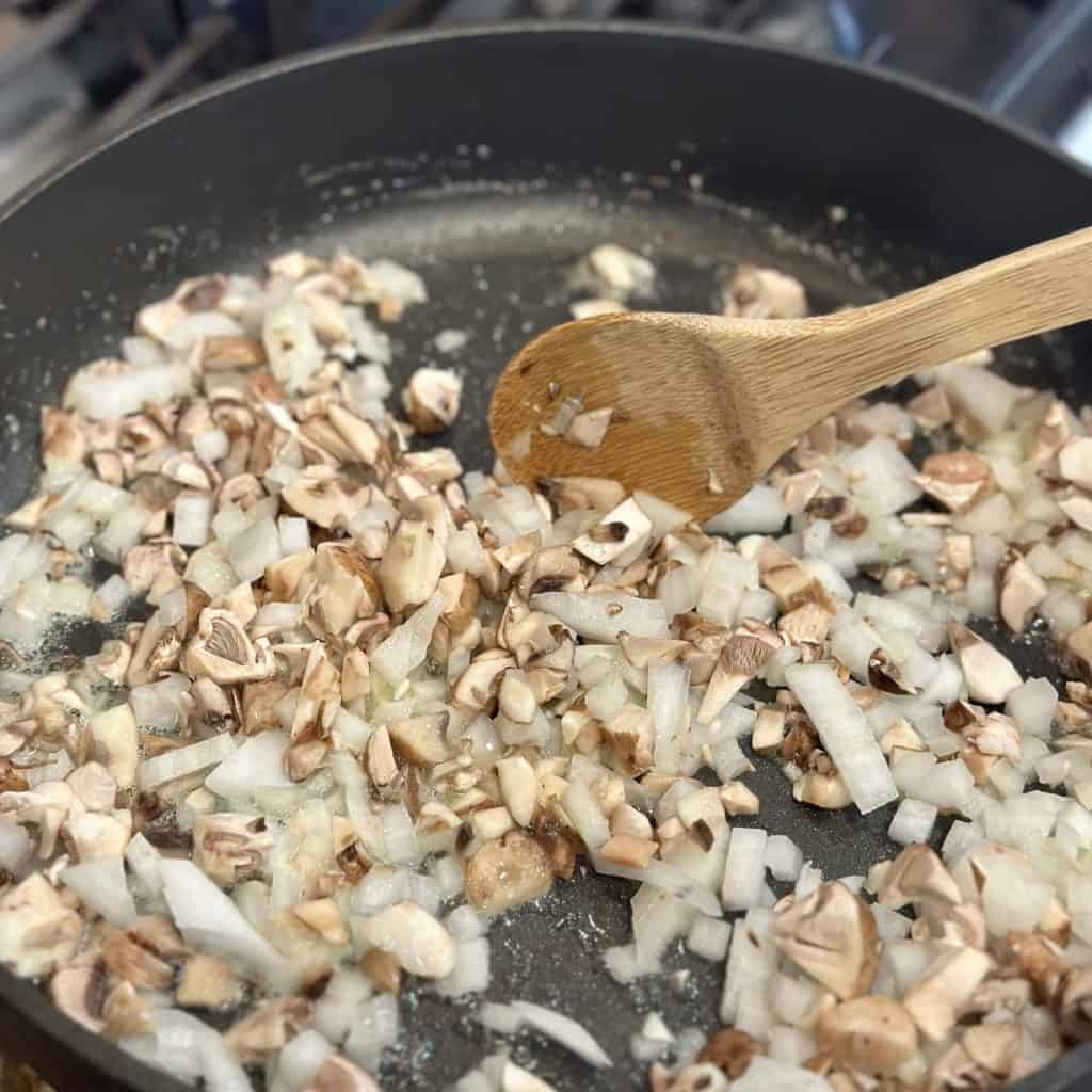 Sautéing onions and mushrooms in a large skillet.