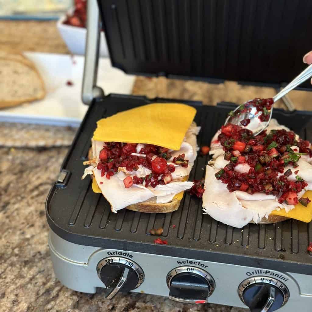 Spreading cranberry salsa on a panini sandwich.