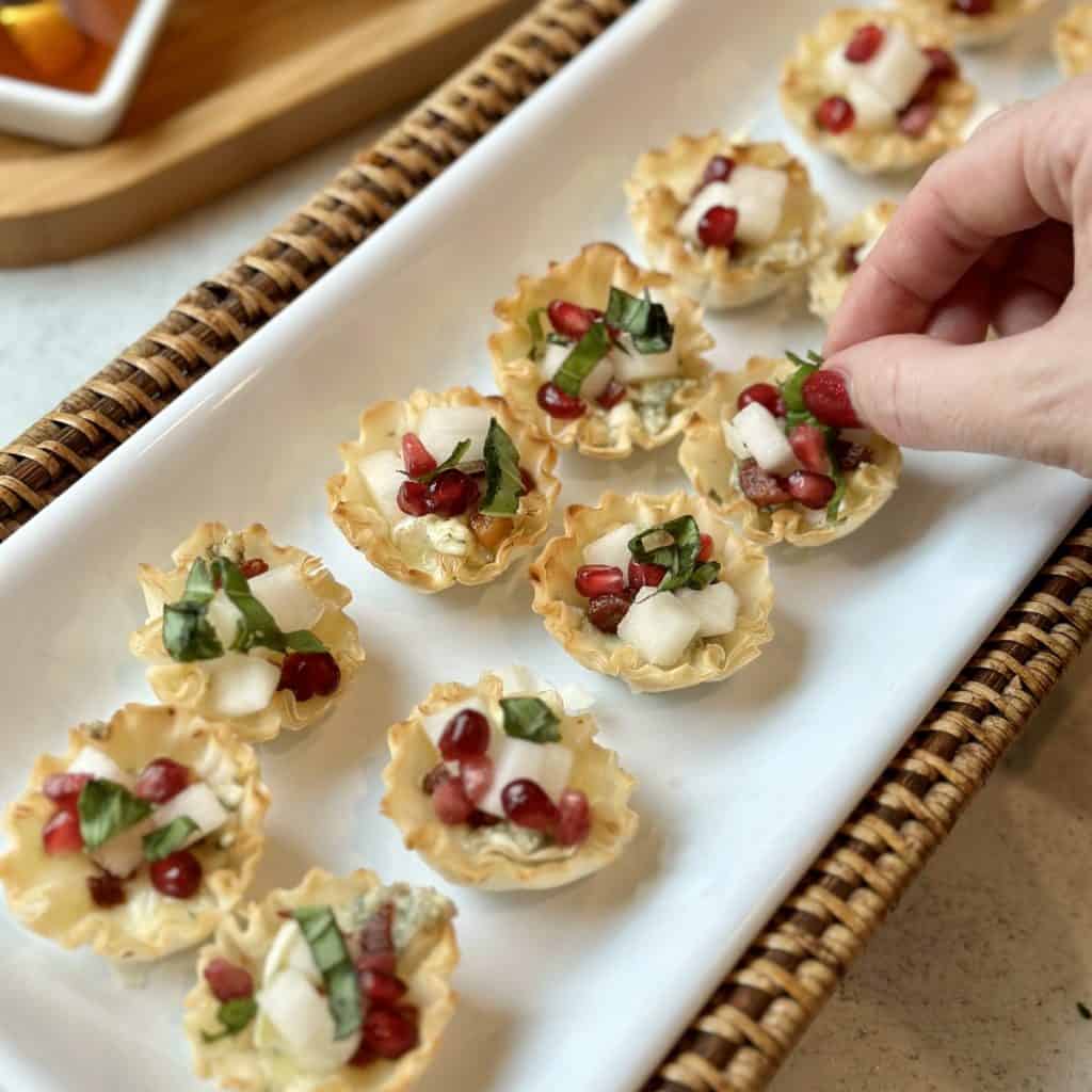 Adding basil to the top of a appetizer bite.