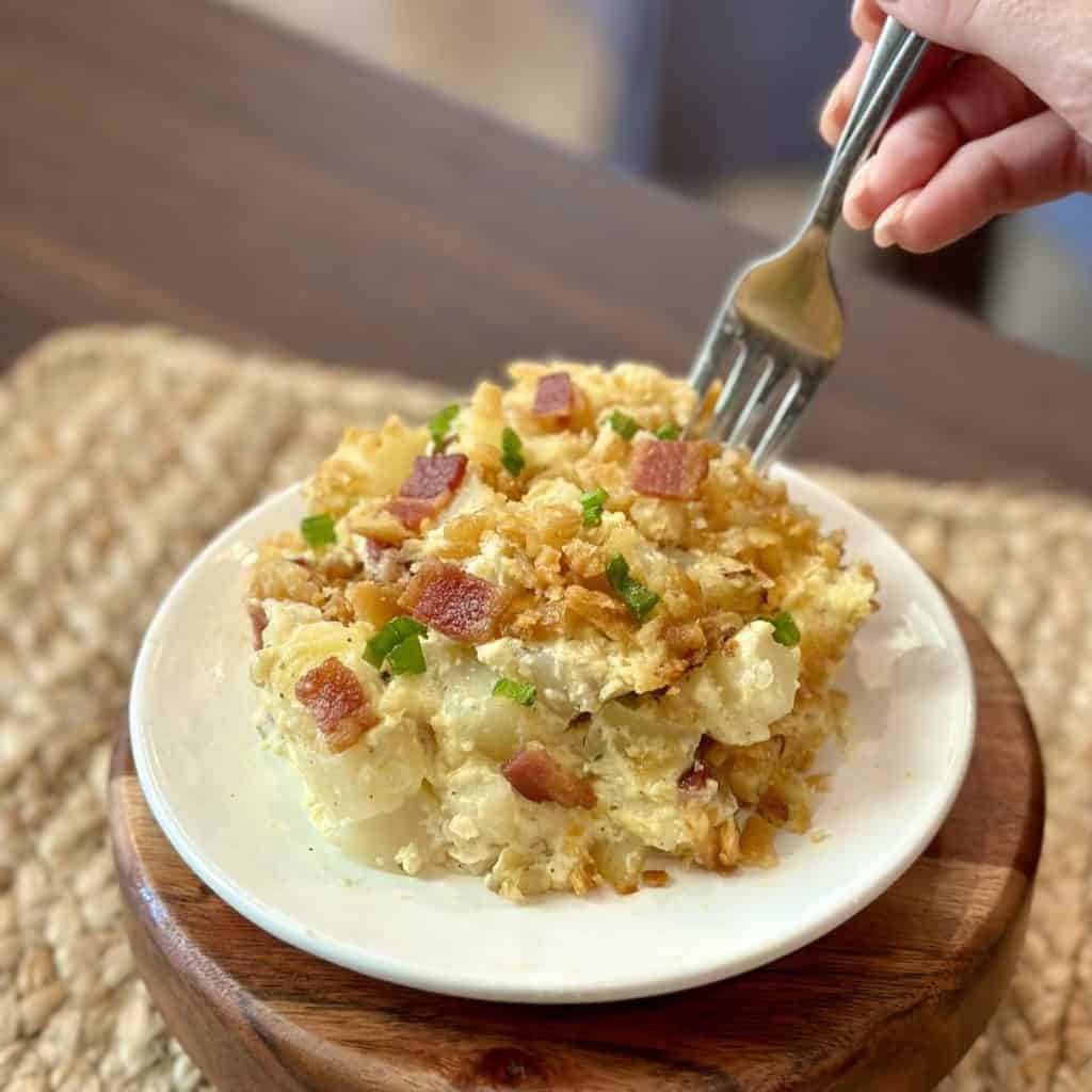 A fork getting a bite of potato casserole.