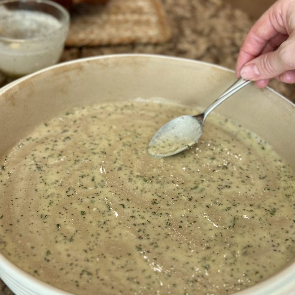 Spreading garlic butter in a baking dish.