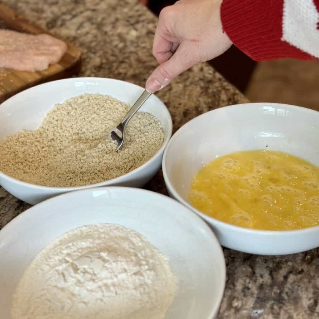 Mixing coatings for chicken parmesan.