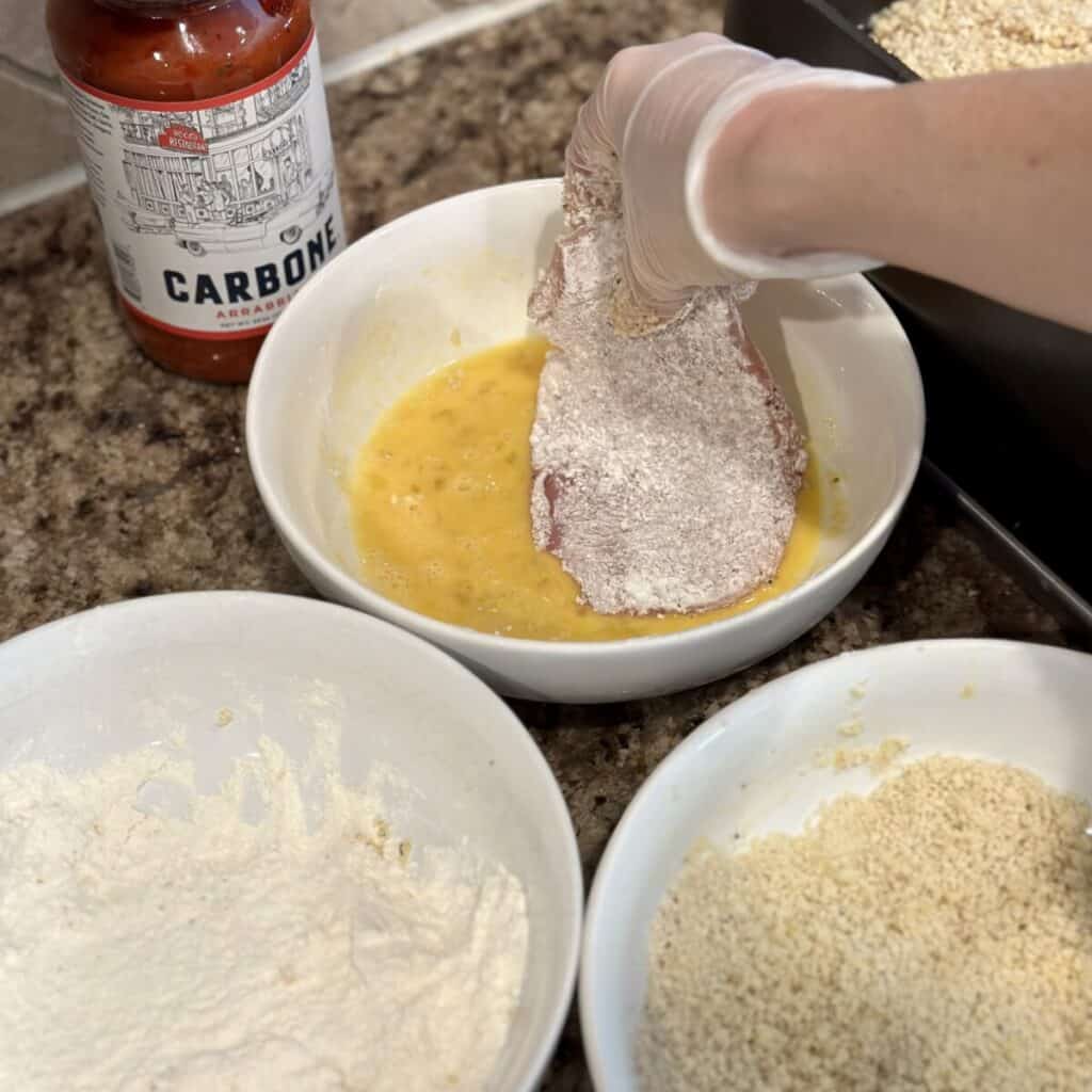 Coating chicken with egg yolk and bread crumbs.