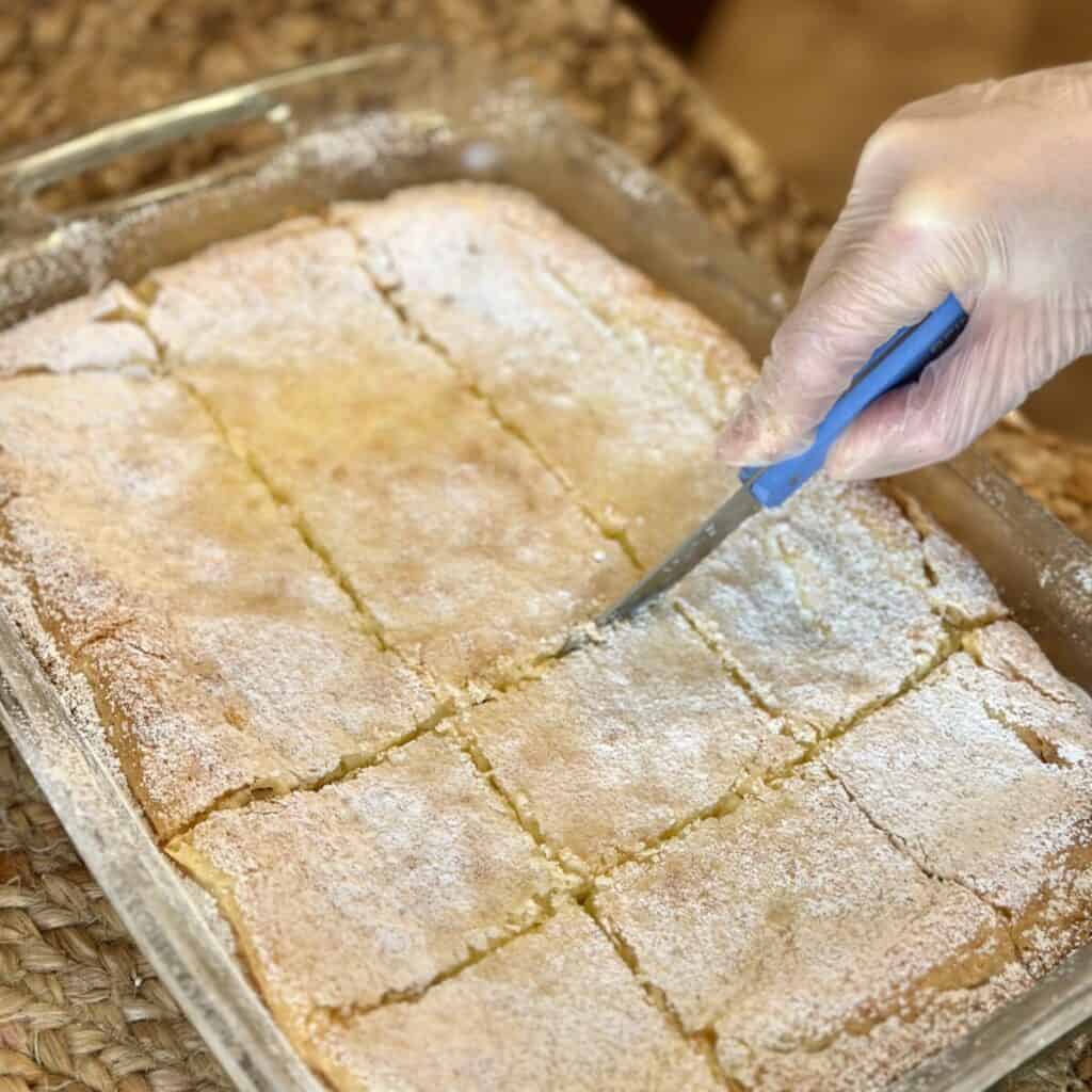 Slicing yum yum bars in a pan.