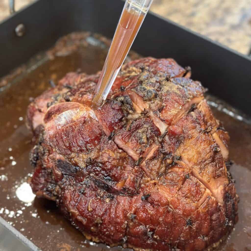 Basting a ham in a roasting pan.