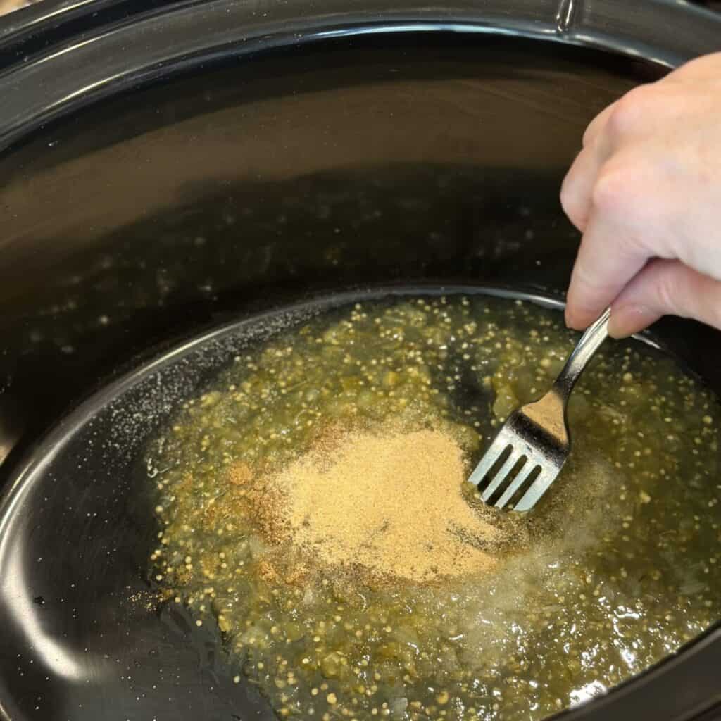 Mixing together the ingredients in a crockpot for green chili chicken.