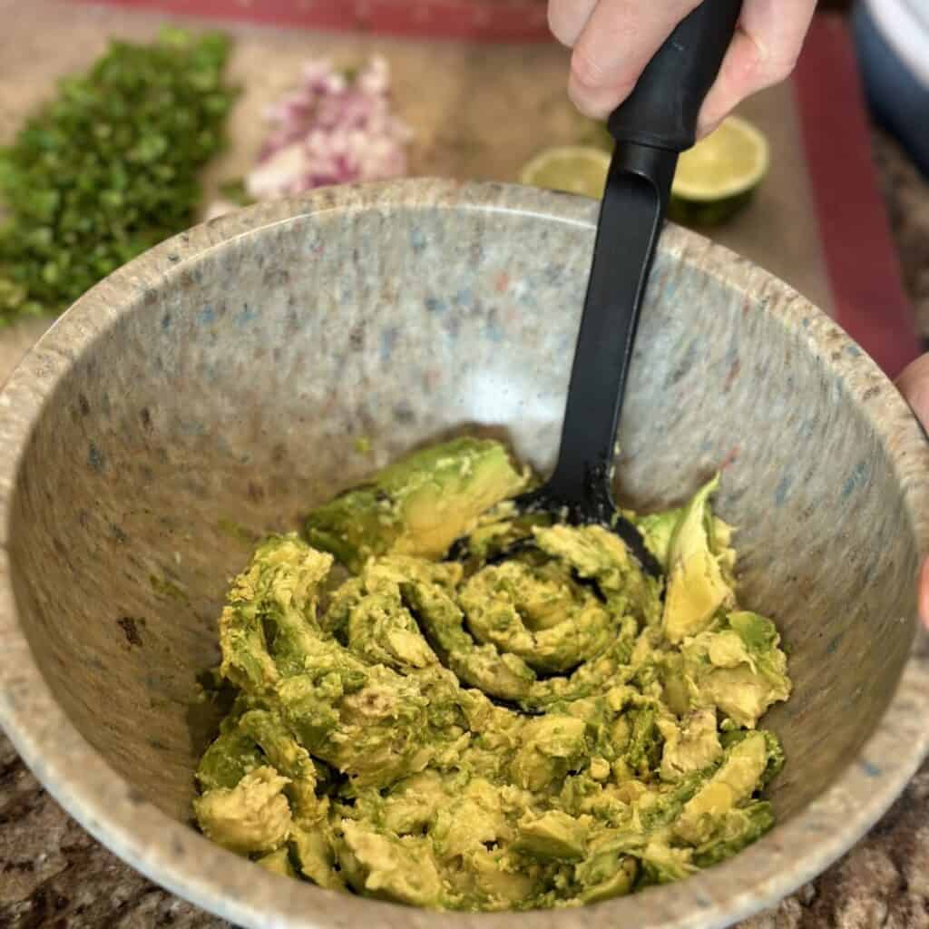 Mashing avocados in a bowl.