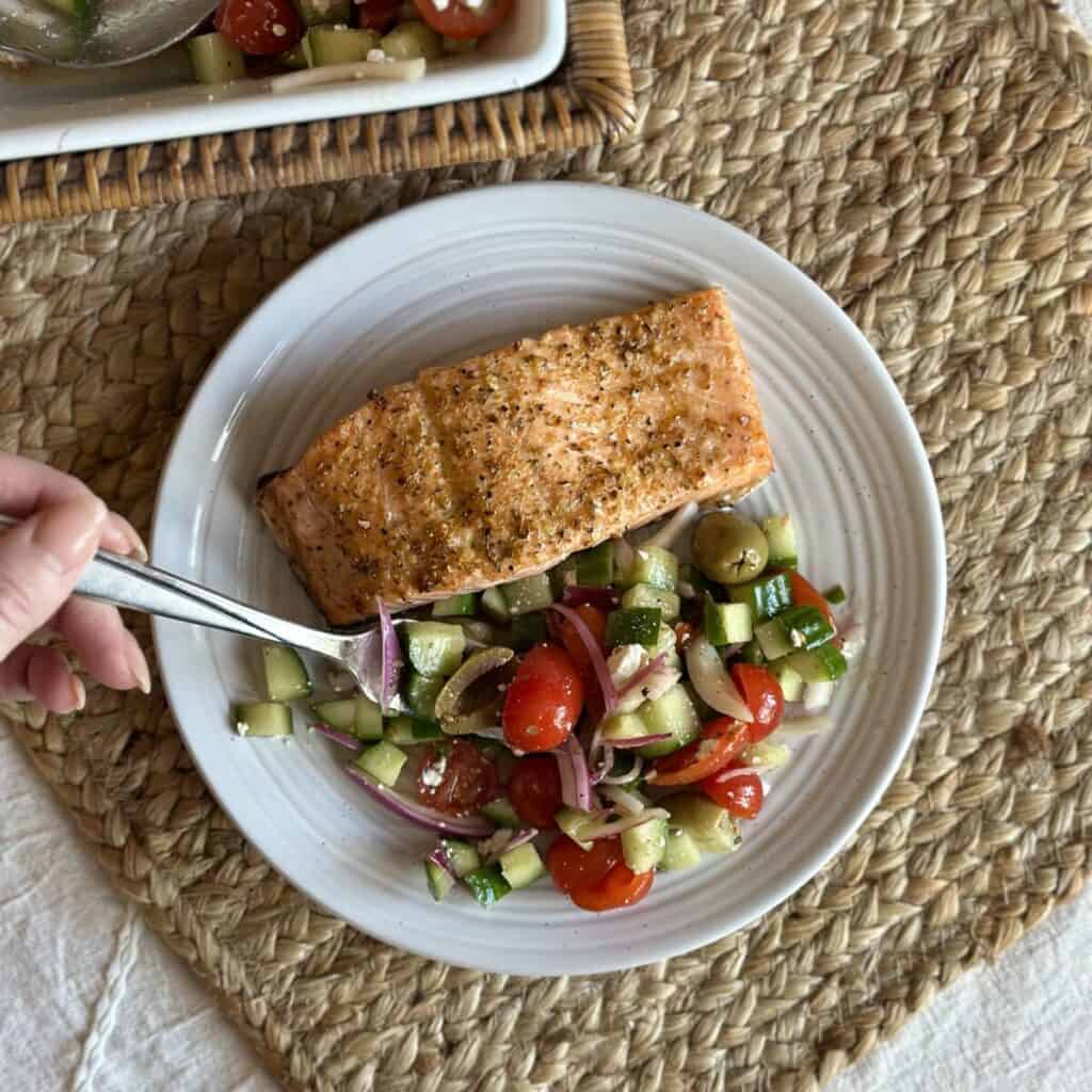 A plate of salmon and cucumber tomato salad.