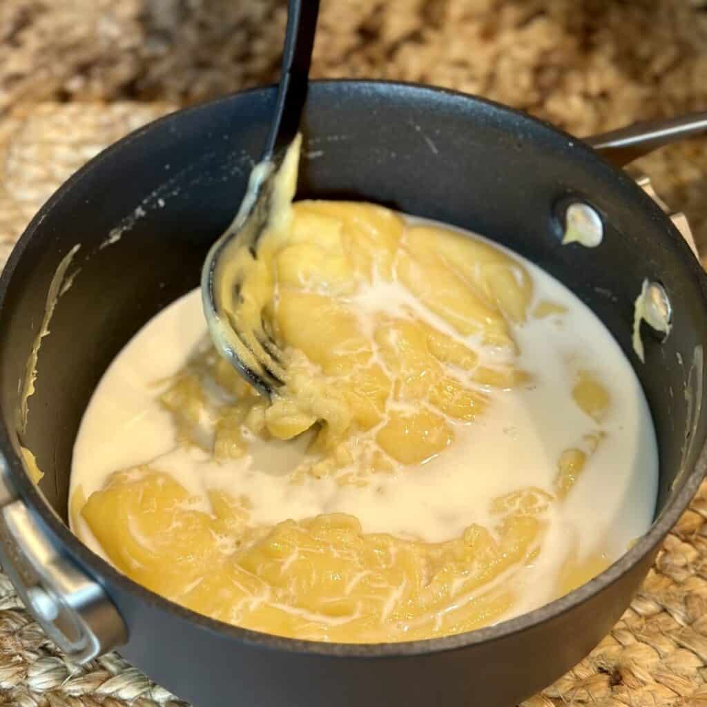 Adding milk to pudding in a saucepan.