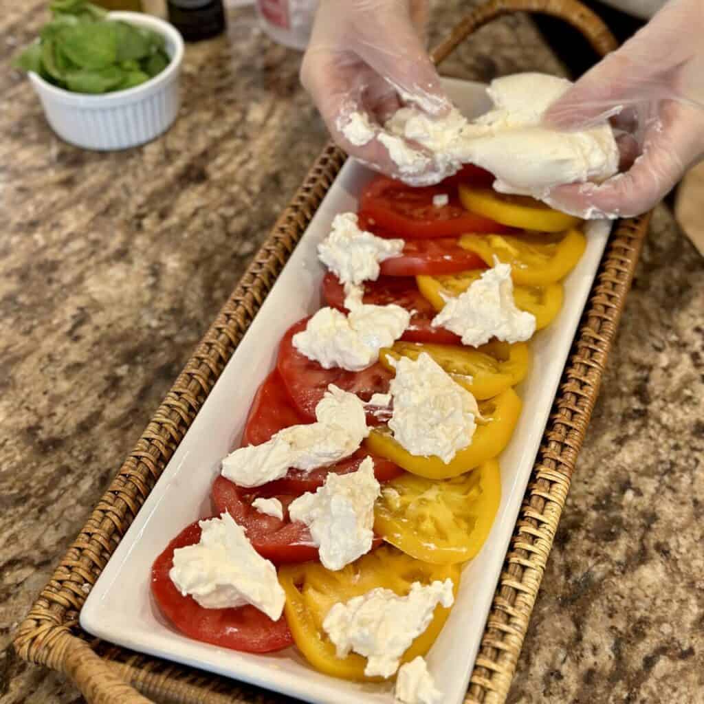 Adding burrata to tomatoes.