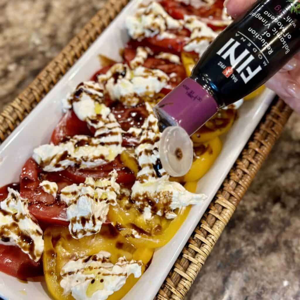 Adding balsamic glaze to burrata caprese.