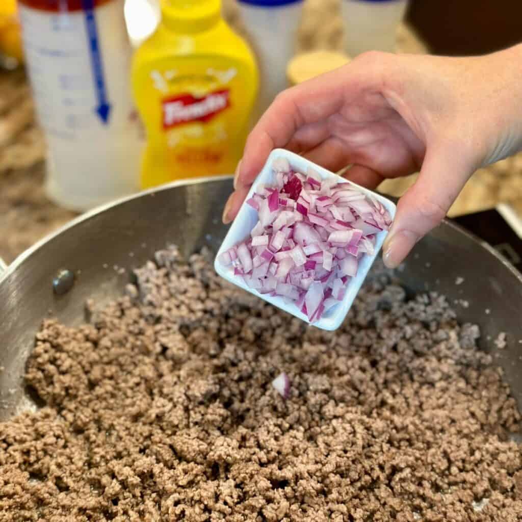 Adding onions to beef.