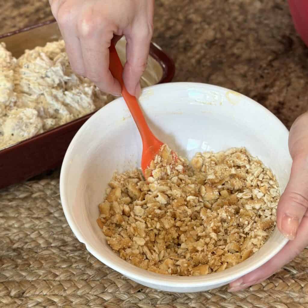 Mixing together butter and crackers.