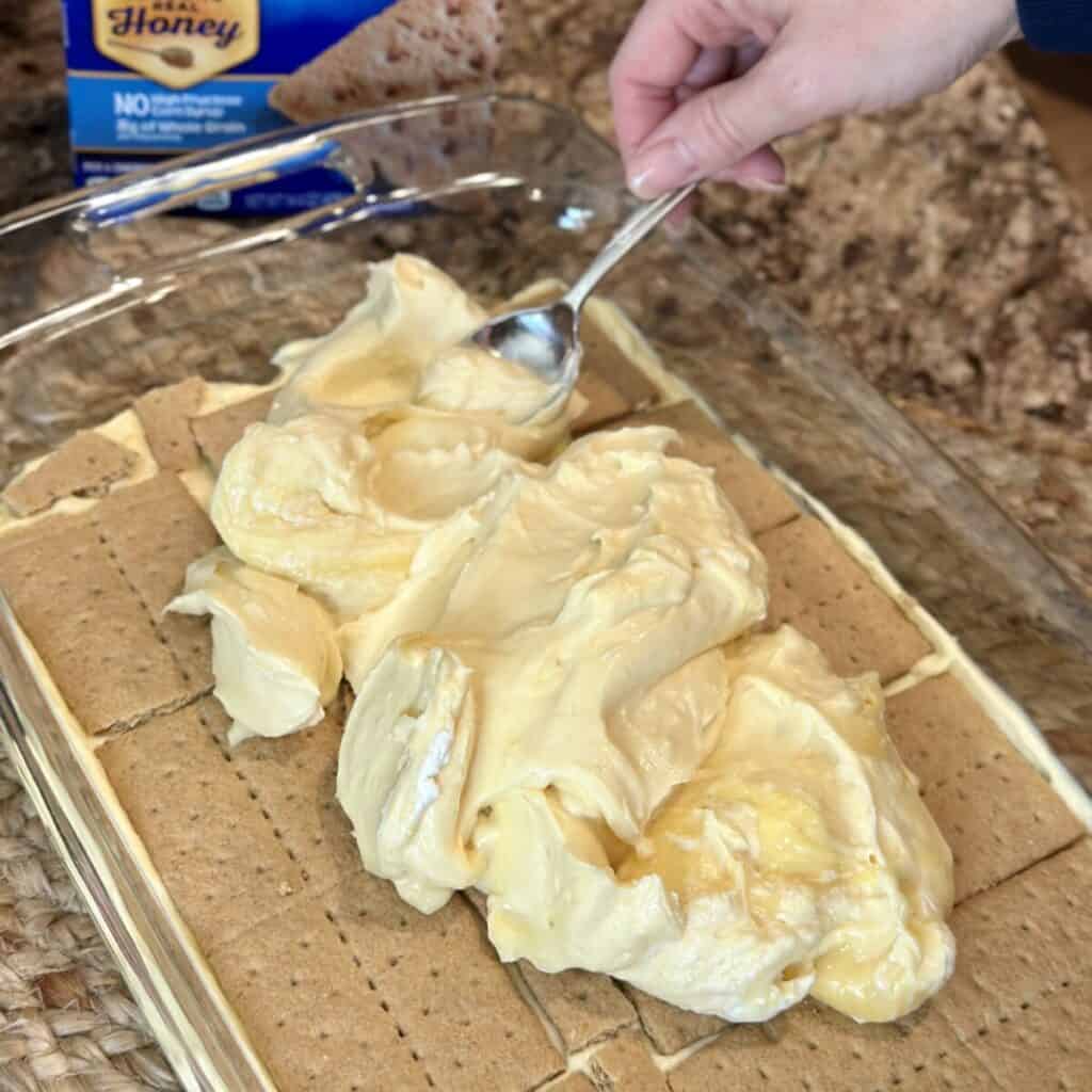 Spreading a second layer of pudding on graham crackers.