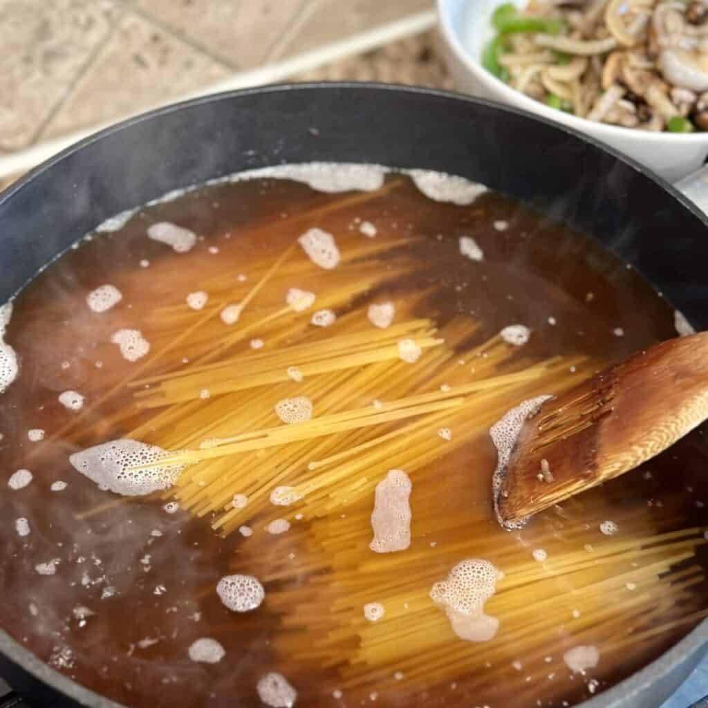 Cooking spaghetti in broth.