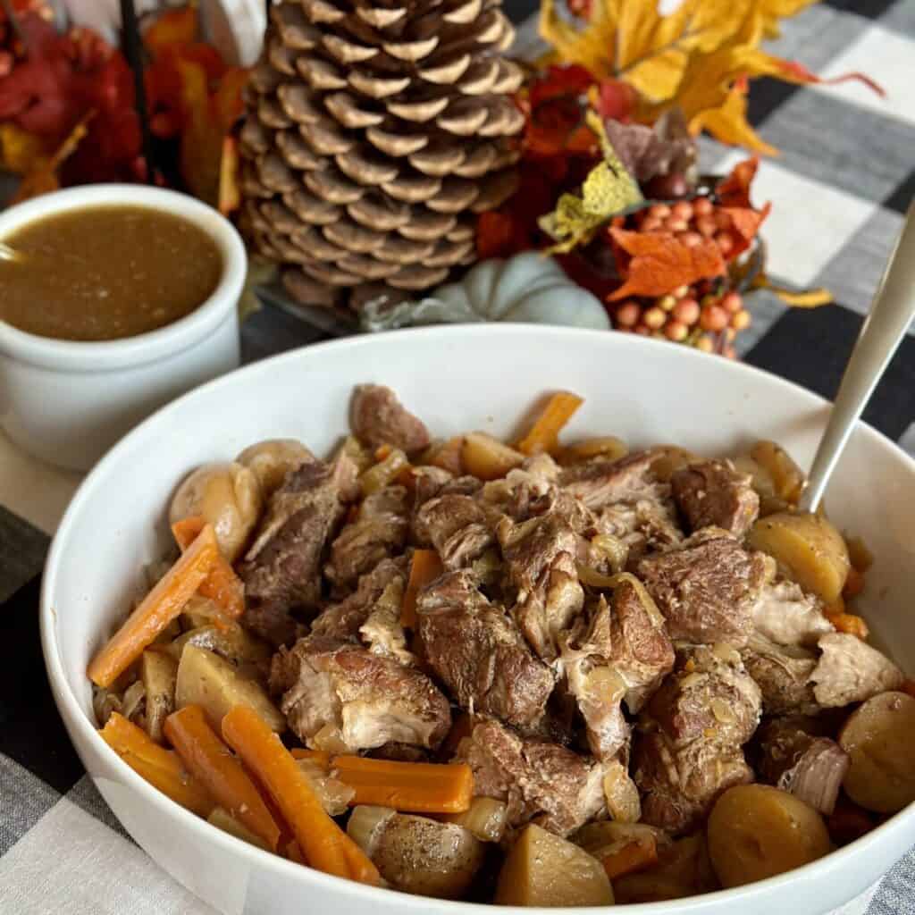 A bowl of country style ribs and vegetables.