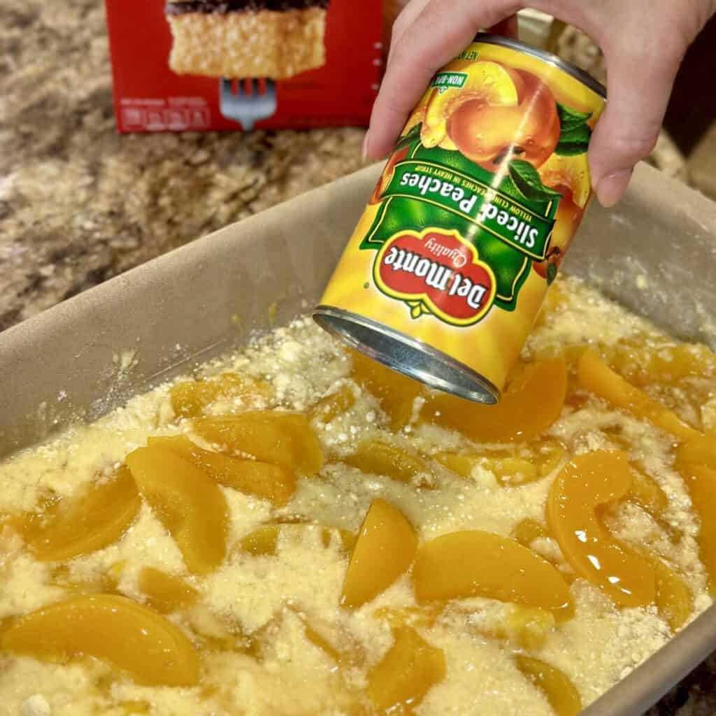 Adding peaches to a cobbler dish.