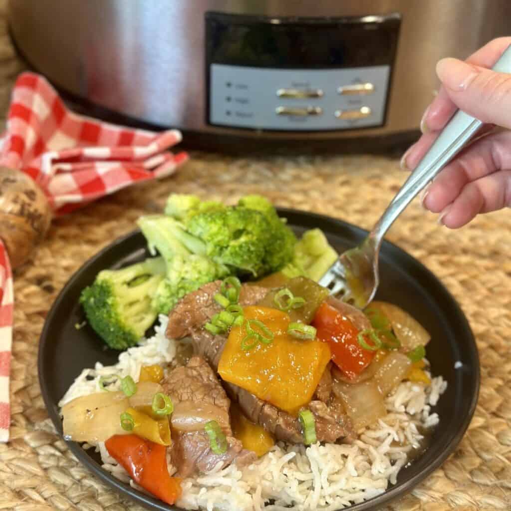 Slow cooker pepper steak and rice with veggies on a plate.