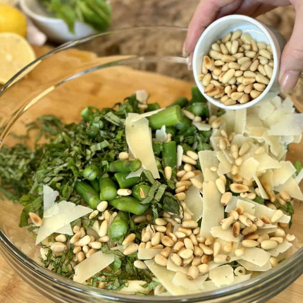 Adding pine nuts to pasta salad.