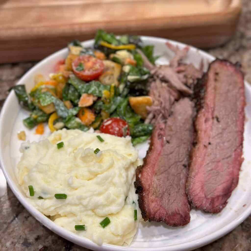 A plate of mashed potatoes, salad and meat.