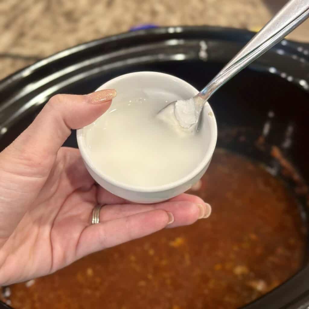 Adding a cornstarch slurry to a crockpot.