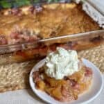 A serving of strawberry peach cobbler and whipped cream on a plate.