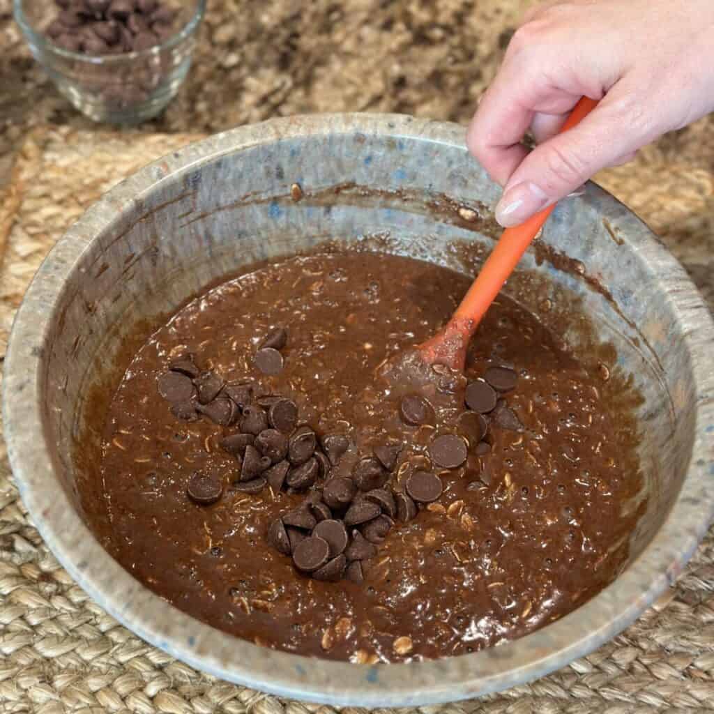 Folding chocolate chips in baked chocolate oatmeal.