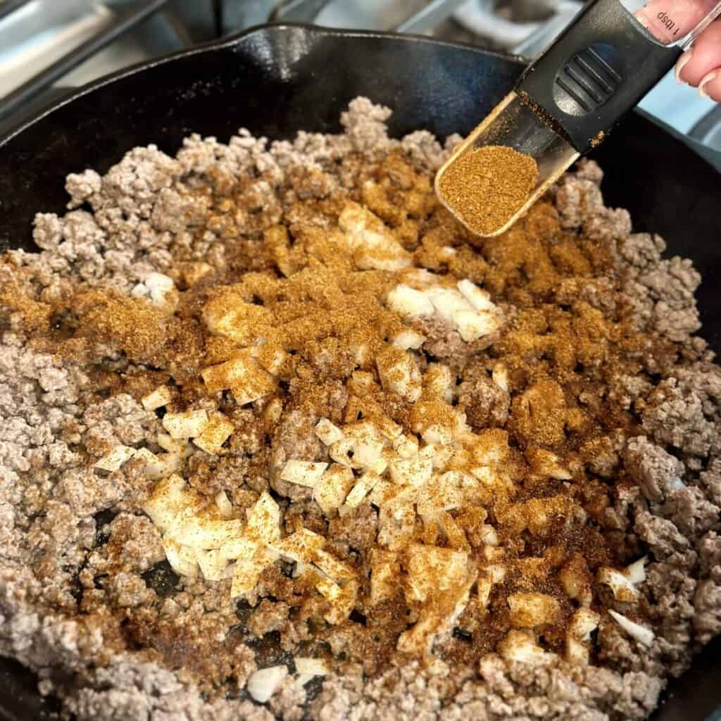 Seasoning ground beef in a skillet.