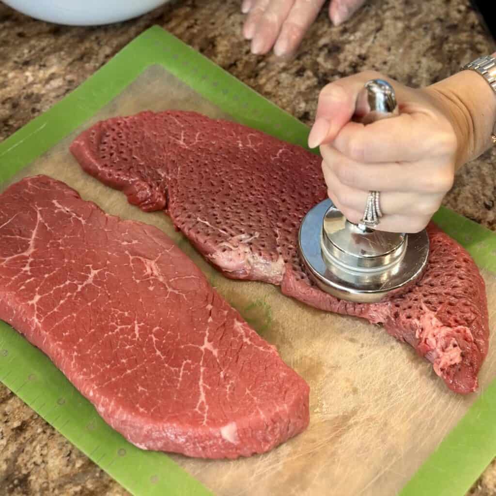 Pounding steaks with a meat tenderizer.