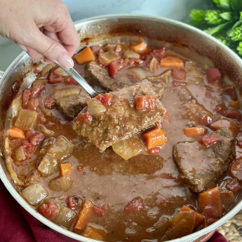 Getting a swiss steak our of a pan of gravy.