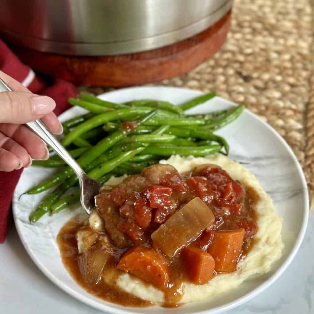 Swiss steak, mashed potatoes and green beans on a plate.