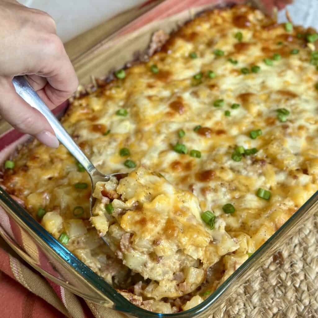 A spoon of cooked cheesy ham and potato casserole.