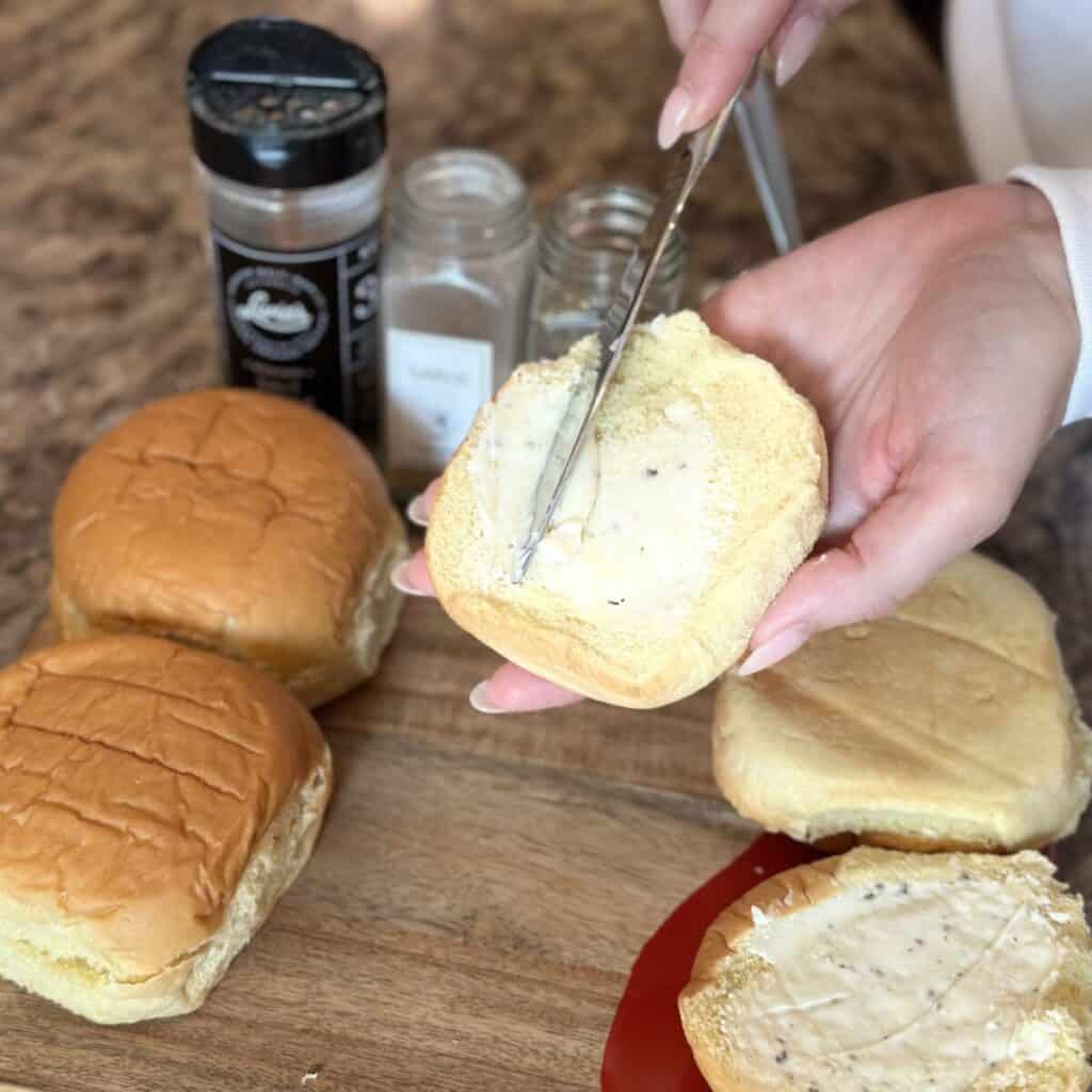 Spreading butter on a hamburger bun.