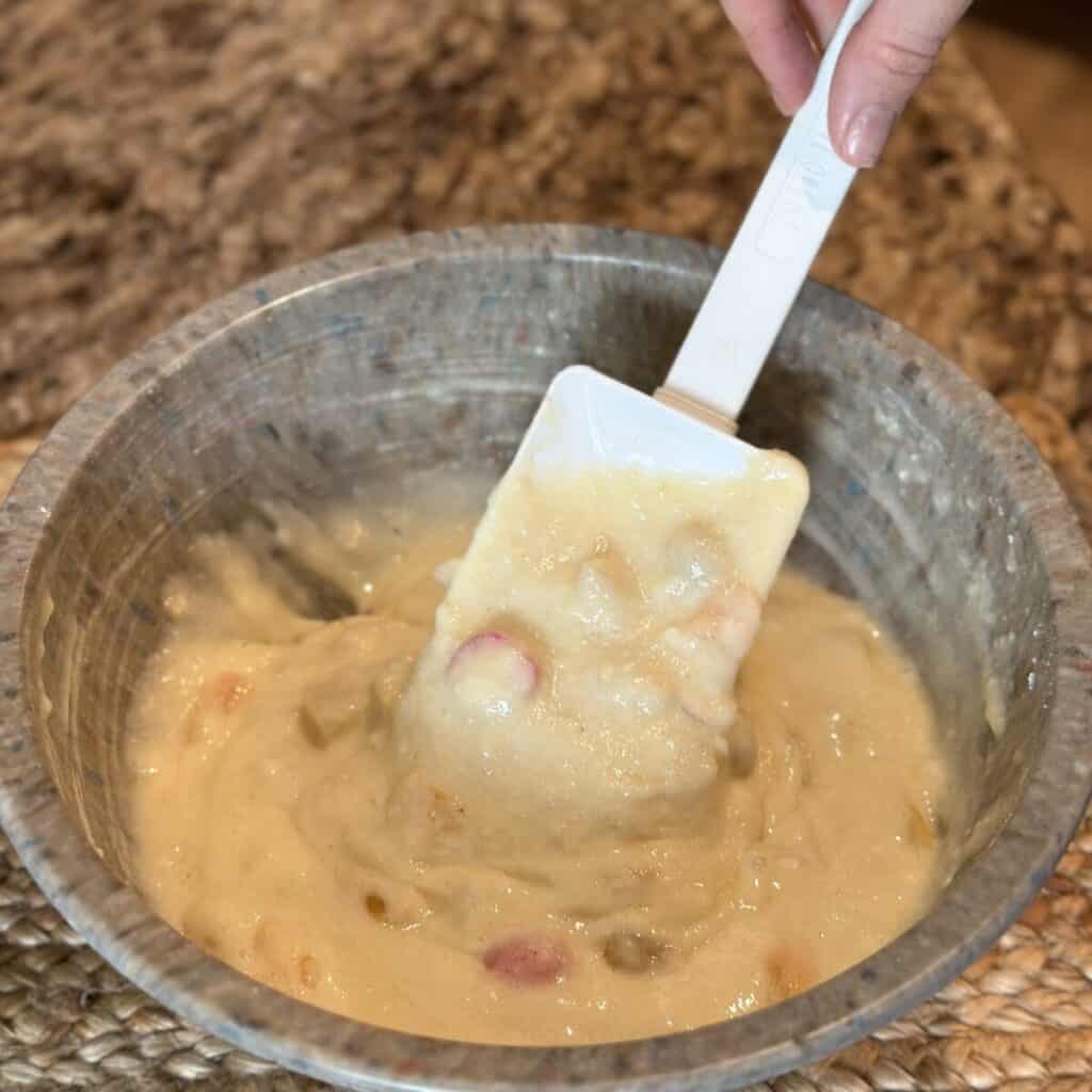 Mixing together batter for fruit cocktail cake in a bowl.