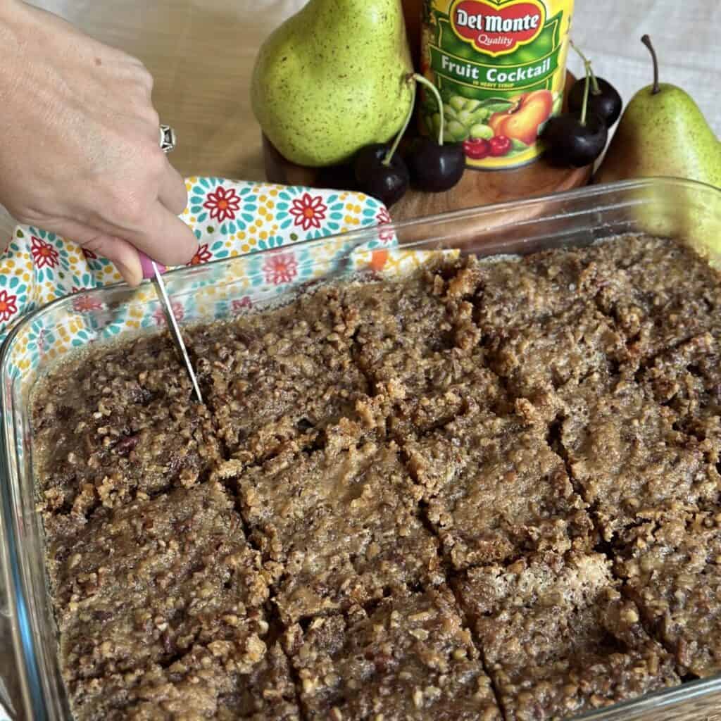 Cutting slices of a fruit cocktail cake.