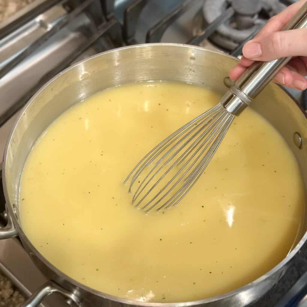 Whisking together broth and soup in a pan.